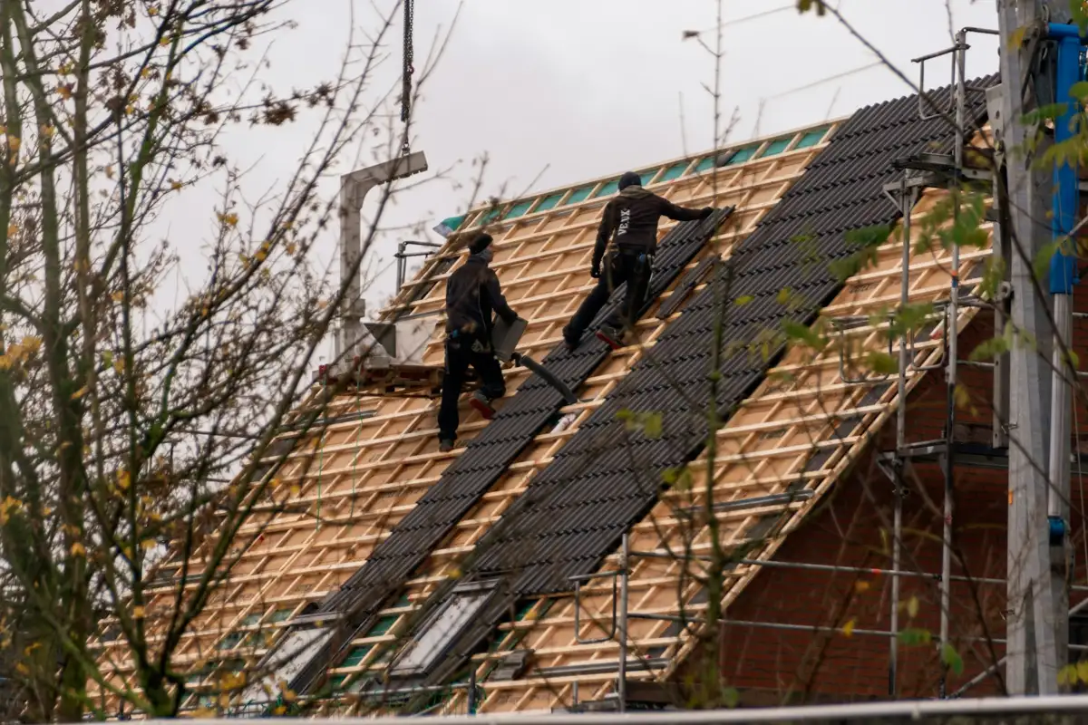 Roofing crew installing architectural shingles on a steep roof